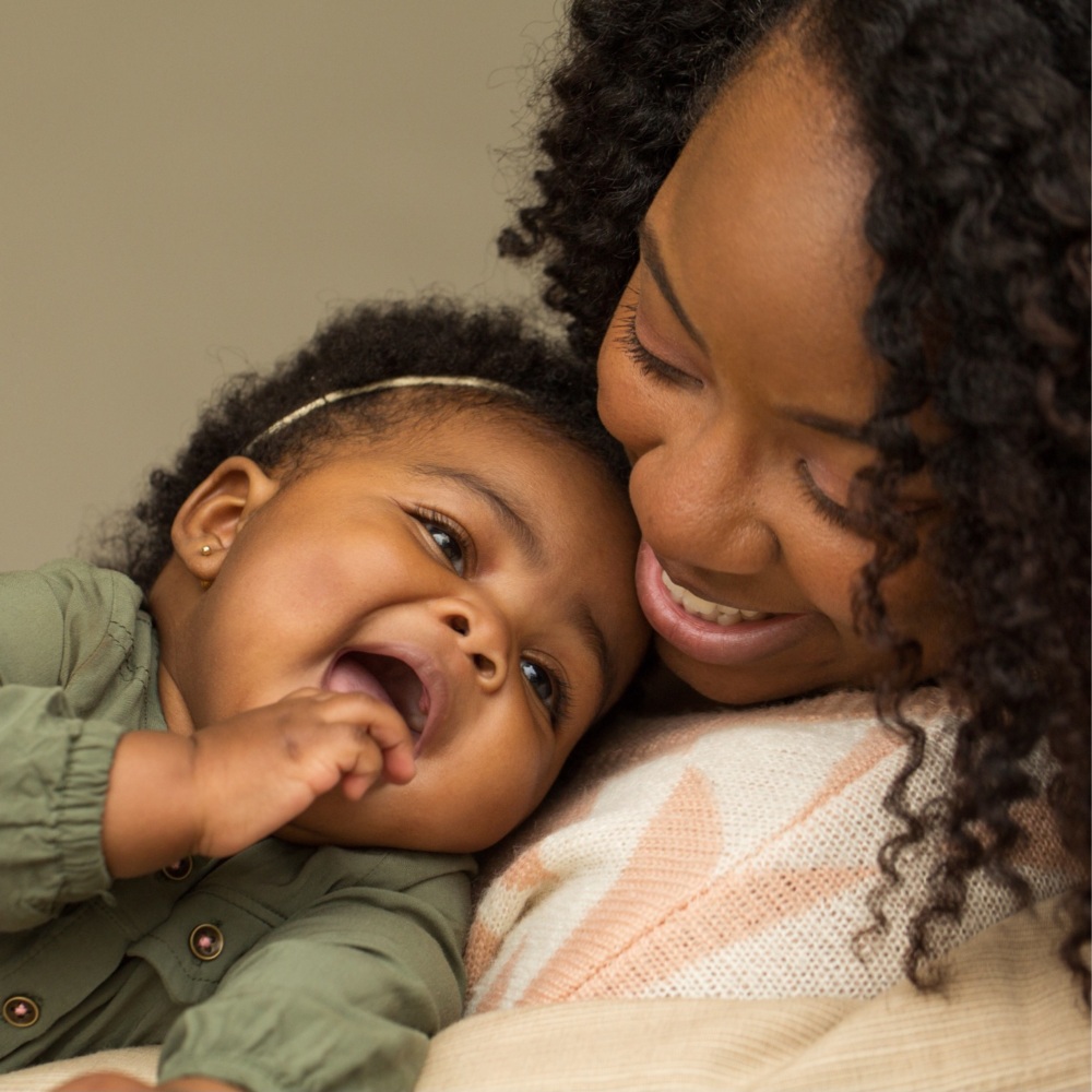 A black mother holds her smiling baby.